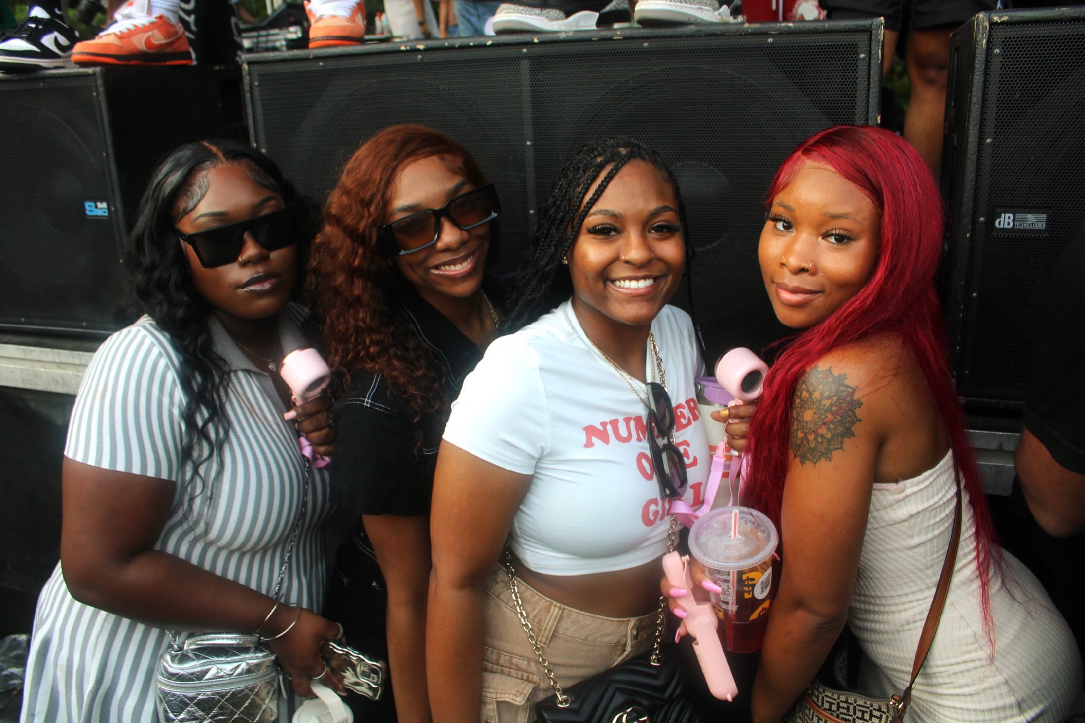 Four women posing together in front of stage speakers at an outdoor concert